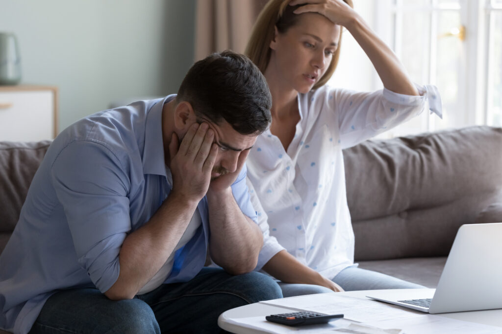 Savoir gérer les imprévus Un couple assis sur un canapé entrain de faire les comptes